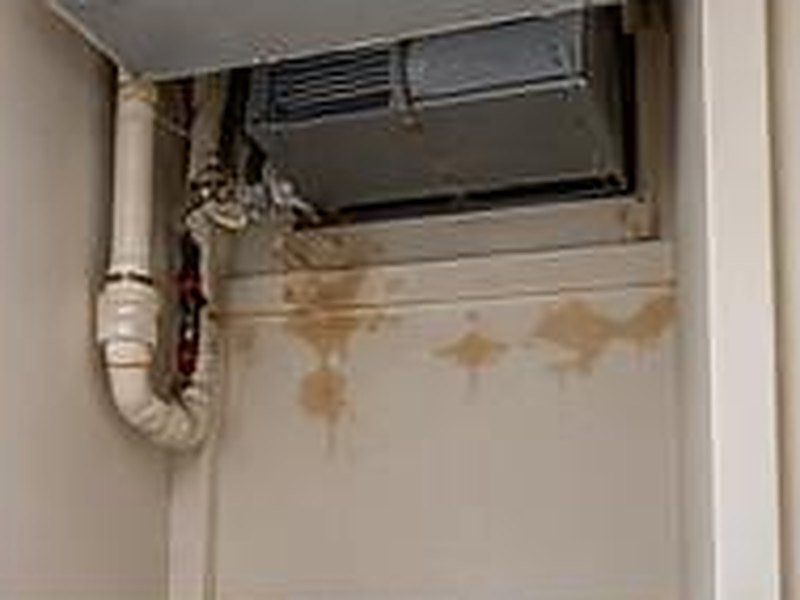 Air handler closet with water stains on the wall below