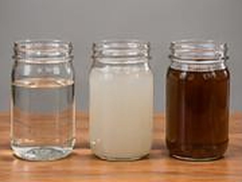 Three jars of clear, cloudy and dark water on a workbench