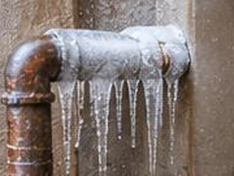 Frozen copper pipe covered in frost and icicles