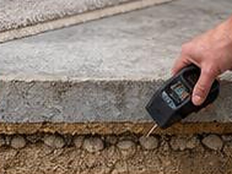 Moisture meter pressed against a concrete slab floor